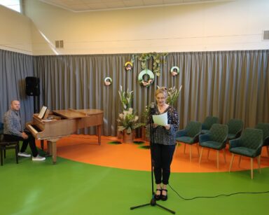 Sala. Scena. Przy fortepianie mężczyzna w koszuli w kratę i ciemnych spodniach, przy mikrofonie kobieta w ciemnym stroju.