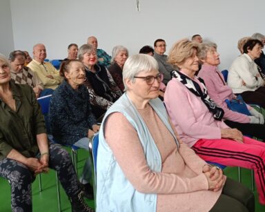 Zbliżenie. Grupa seniorów z uśmiechem na ustach ogląda wywiad.