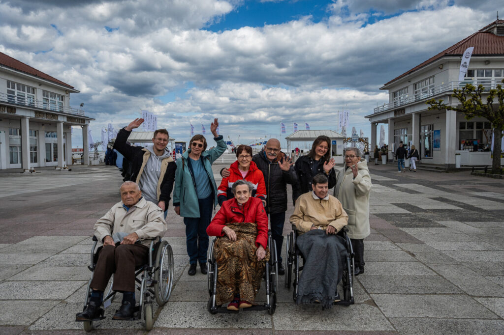 Sopockie Molo. Do grupowego zdjęcia ustawili się młodzi ludzie, seniorzy i seniorzy na wózkach.